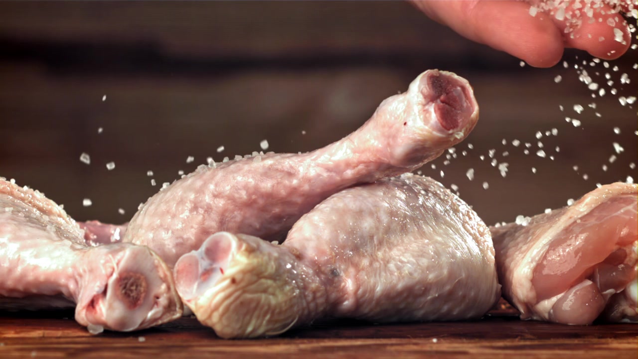 Salatura di pezzi di pollo crudo al rallentatore