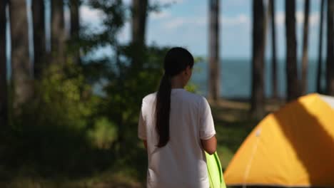 woman camping by a lake in the forest