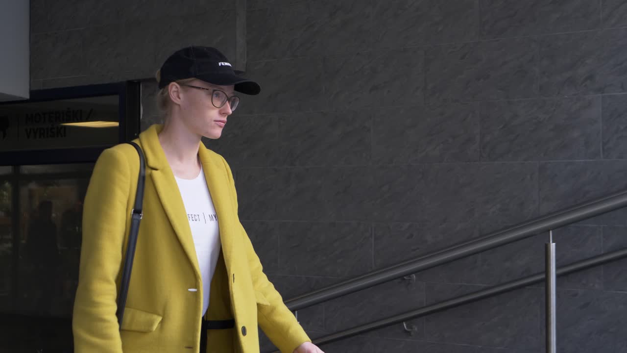 Young Woman in Yellow Coat Walking Up Stairs
