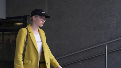 young woman in yellow coat walking up stairs