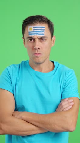 dignified and serious man with uruguayan flag painted on face