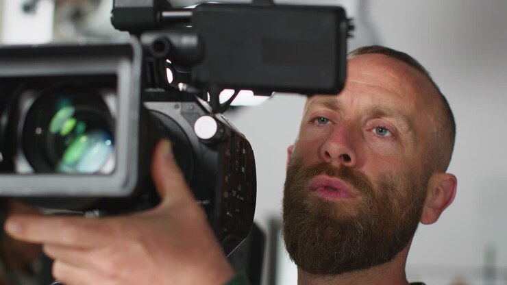 Close Up Of Male Film Camera Operator Looking At Monitor And Focusing Shooting Movie Or Video In Studio