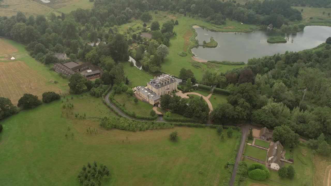 Aerial view flying over Kenwood mansion house with manicured gardens and private lake estate