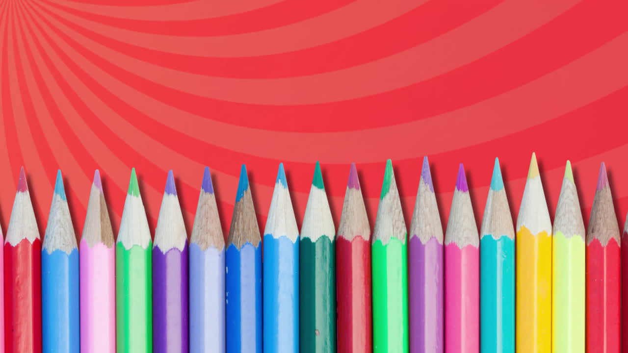 Colorful pencils arranged in row over red spiral animation background