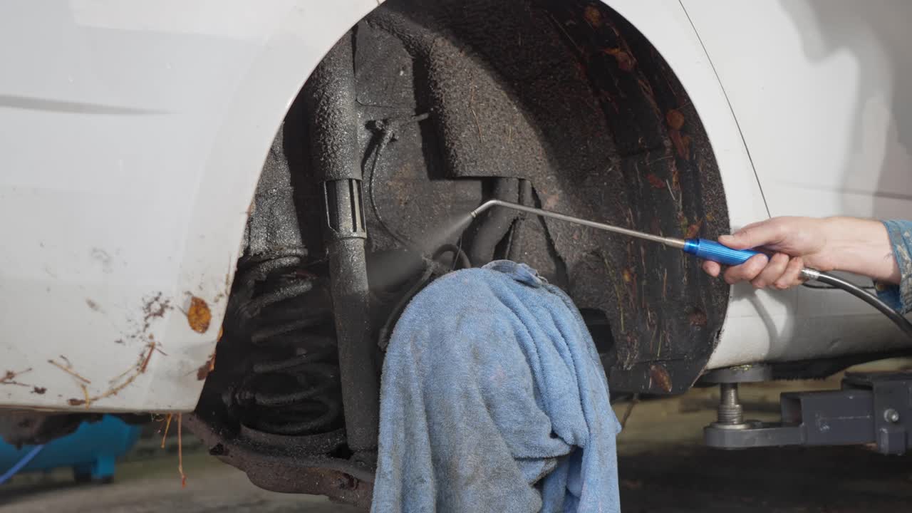 Closeup of DIY lanolin oil rust protection applied with nozzle in garage showing eco friendly corrosion prevention