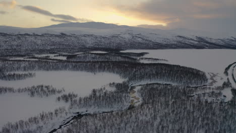 vista aérea a través de la cordillera escandinava cubierta de nieve bosque desierto bajo el horizonte del amanecer