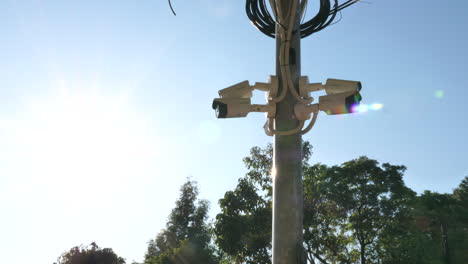 wide shot of security cameras on a post from left with the sun in the back