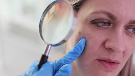 dermatologist examining patient's skin with magnifying glass