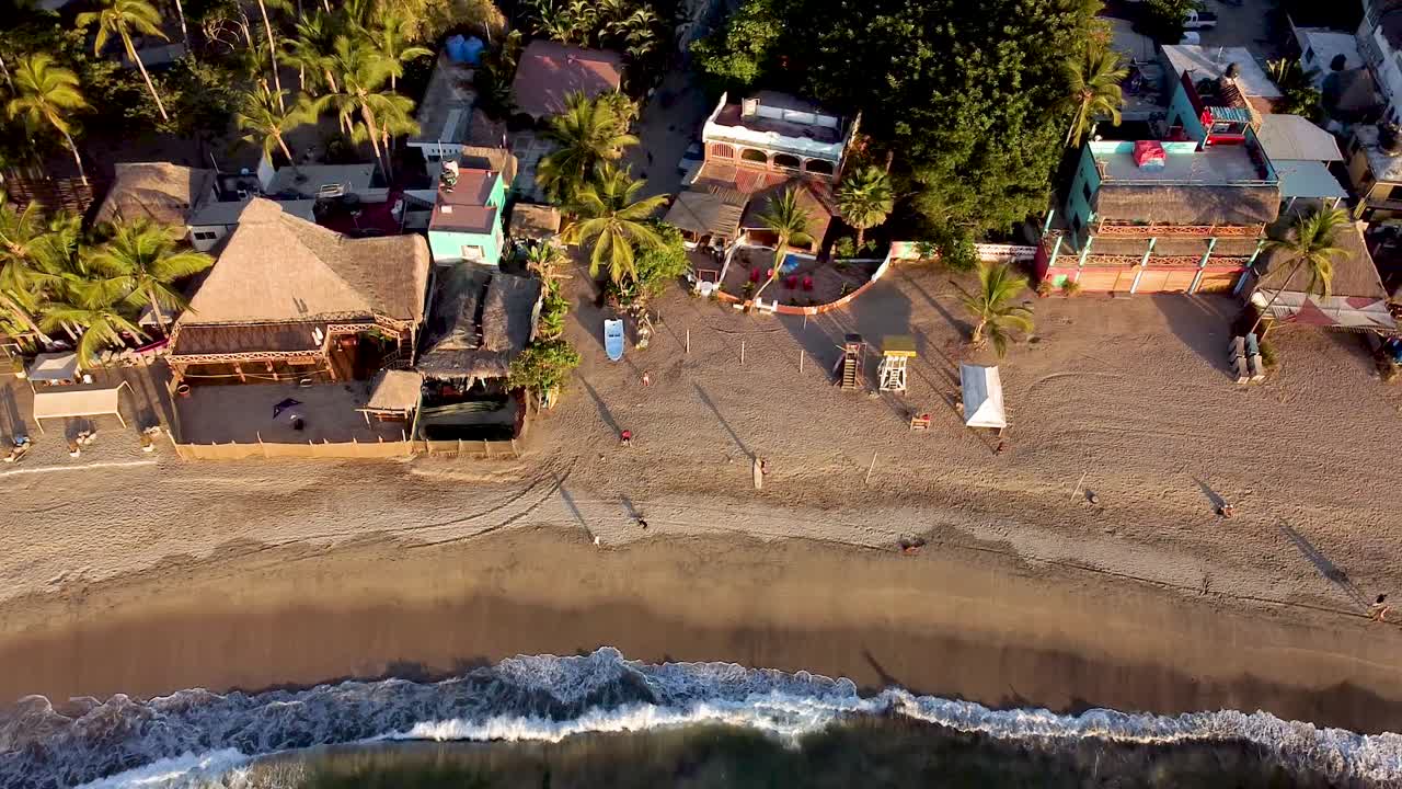 vuelo aéreo sobre la playa principal de sayulita con olas rompiendo en la playa en méxico durante las horas del atardecer