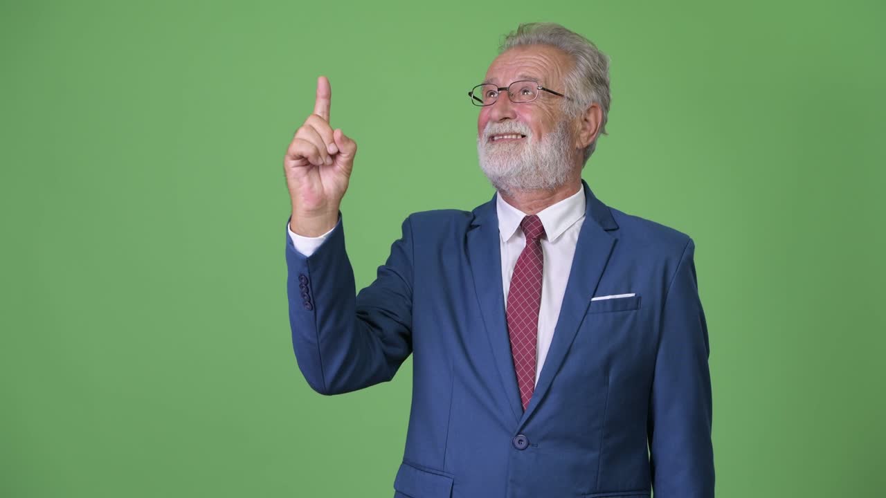 Handsome senior bearded businessman against green background