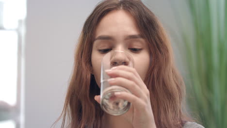 cheerful woman taking vitamin capsule and drinking water from glass in bath room