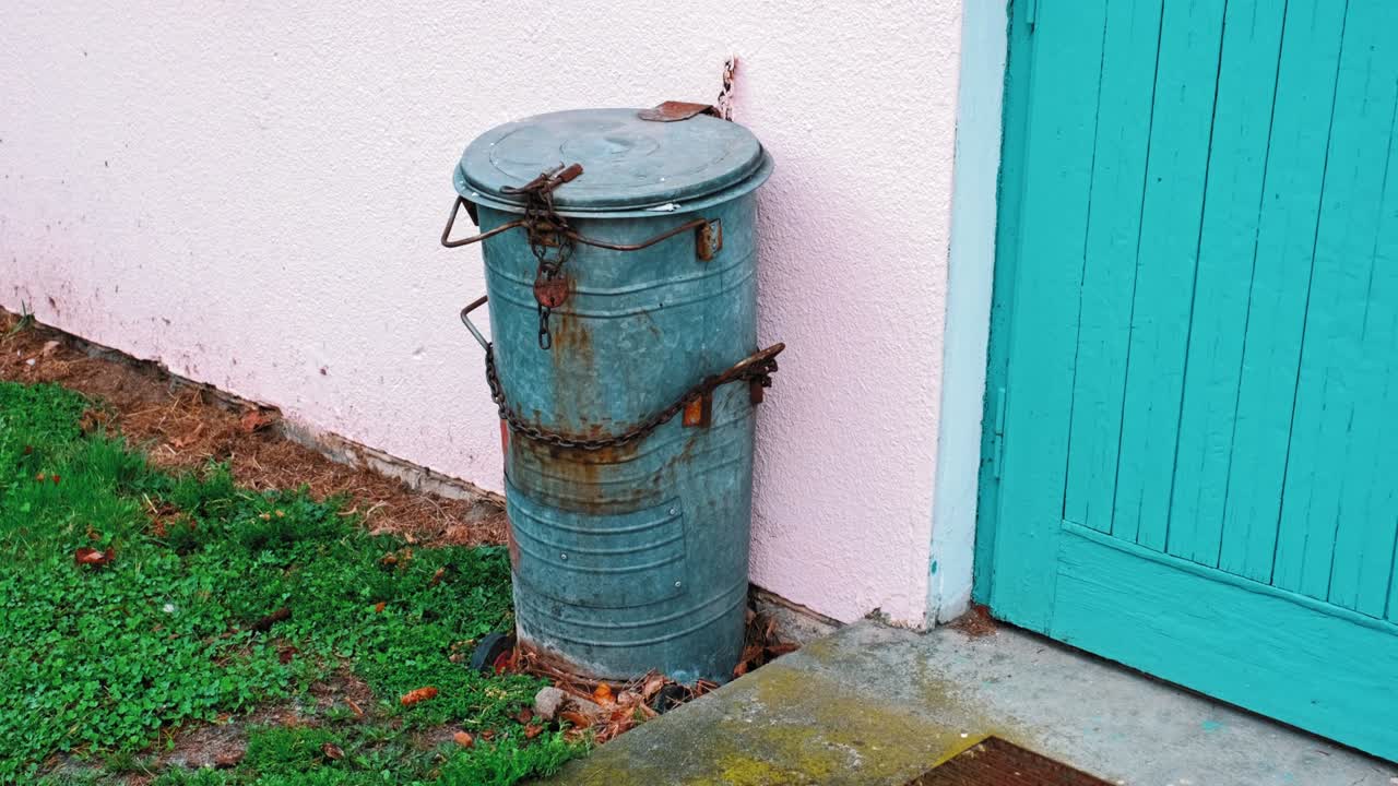 금속 쓰레기통은 에 불법적인 쓰레기를 버리는 것을 막기 위해 녹은 과 사슬로 고정되어 있습니다.