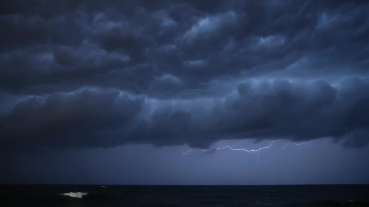 Reacting to rising horizon glow, shelf cloud releasing forked lightning over ocean, lighting waves