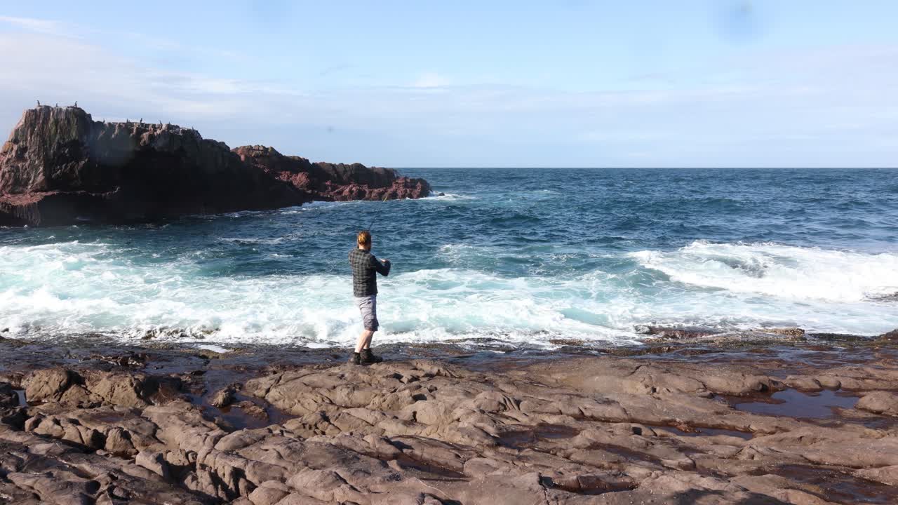 호주에서 큰 바다가 팽창하는 위험한 바위에서 낚싯줄을 던지는 어부
