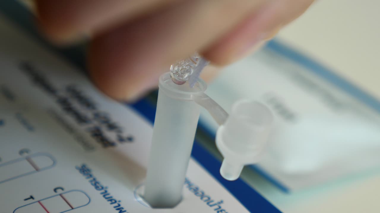 hombre exprime líquido con la mano en un tubo de plástico para probar el coronavirus en casa