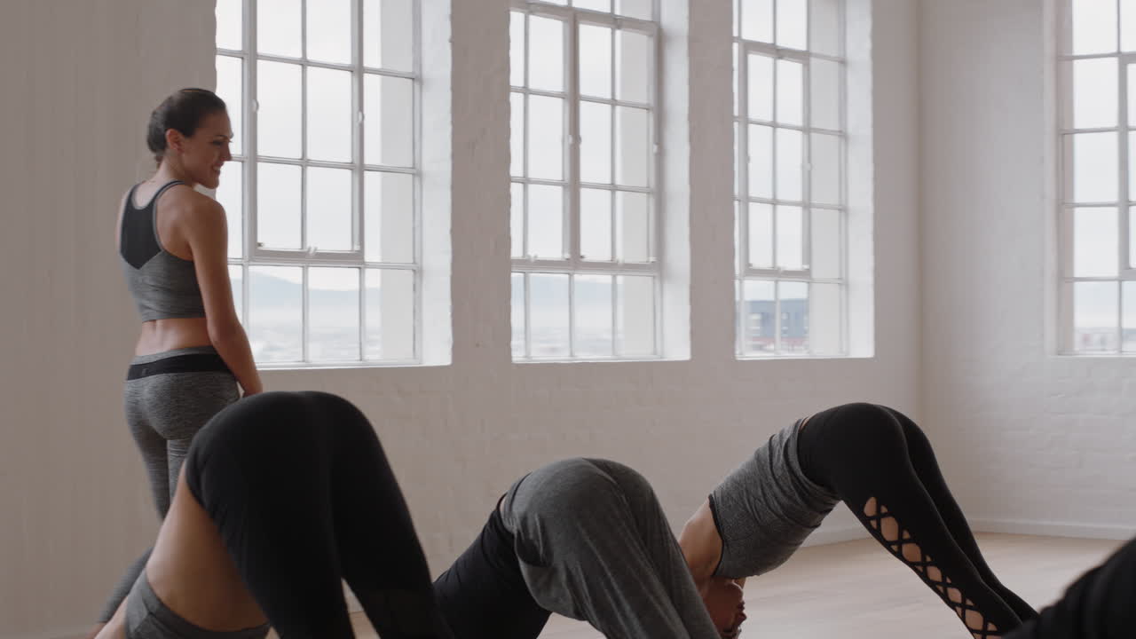 hermosa instructora de yoga enseñando meditación de pose de perro boca abajo con un grupo de mujeres multirraciales disfrutando de un estilo de vida saludable haciendo ejercicio en un gimnasio