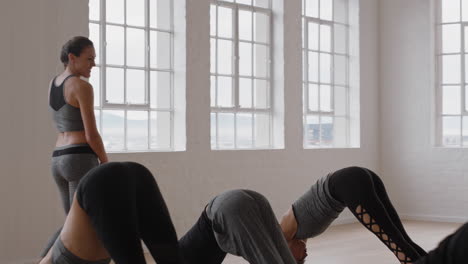 beautiful yoga woman instructor teaching downward-facing dog pose meditation with group of multiracial women enjoying healthy lifestyle exercising in fitness studio