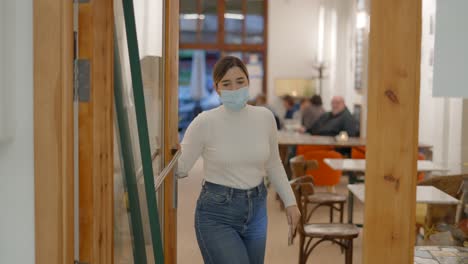woman wearing a mask and using a phone in a modern cafe/office space