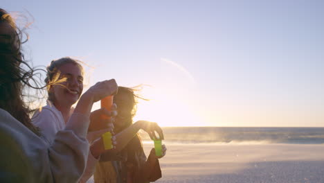 Girl-friends-blowing-bubbles-on-beach-at-sunset-slow-motion