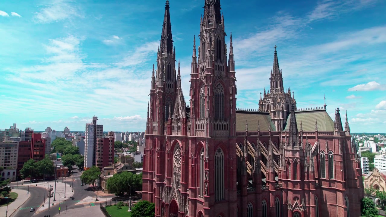Ripresa aerea con drone in volo in avanti e in ascesa verso il profilo laterale e le guglie principali della Cattedrale neogotica di La Plata, con vista su Plaza Moreno a La Plata, Argentina