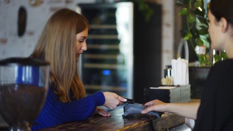 En-La-Cafetería-La-Mujer-Paga-Por-Teléfono-Móvil-Sin-Contacto-Al-Sistema-De-Tarjeta-De-Crédito,-Cámara-Lenta