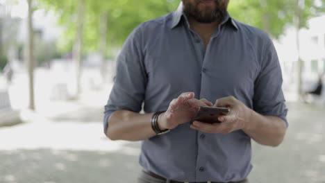 Captura-Recortada-De-Un-Hombre-Usando-Un-Teléfono-Móvil-Al-Aire-Libre