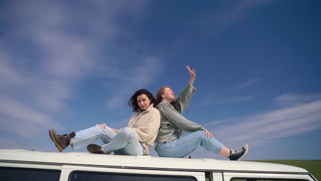 dos chicas jóvenes en el techo de una caravana en medio del campo