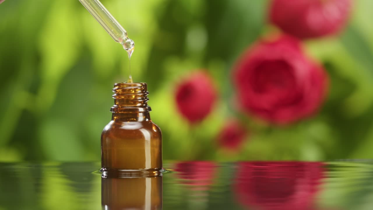 Dripping oil from pipette into bottle close-up, plant juice. Making aroma serum on green background. Dropping liquid floral extract, skincare routine, treatment spa concept. Traditional medicine