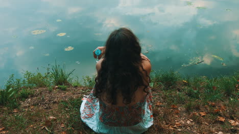 girl sitting on the shore of a lake