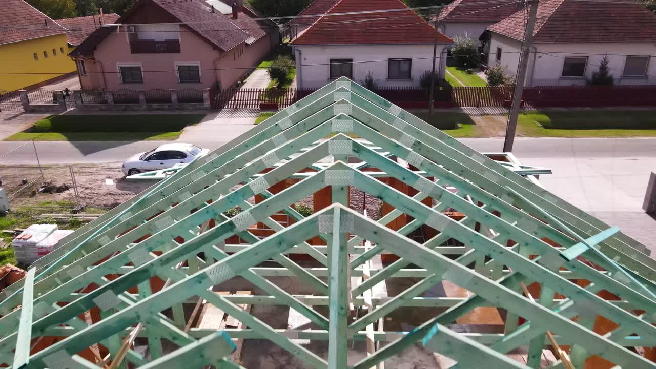 Wooden roof trusses on brick house under construction in rural neighborhood