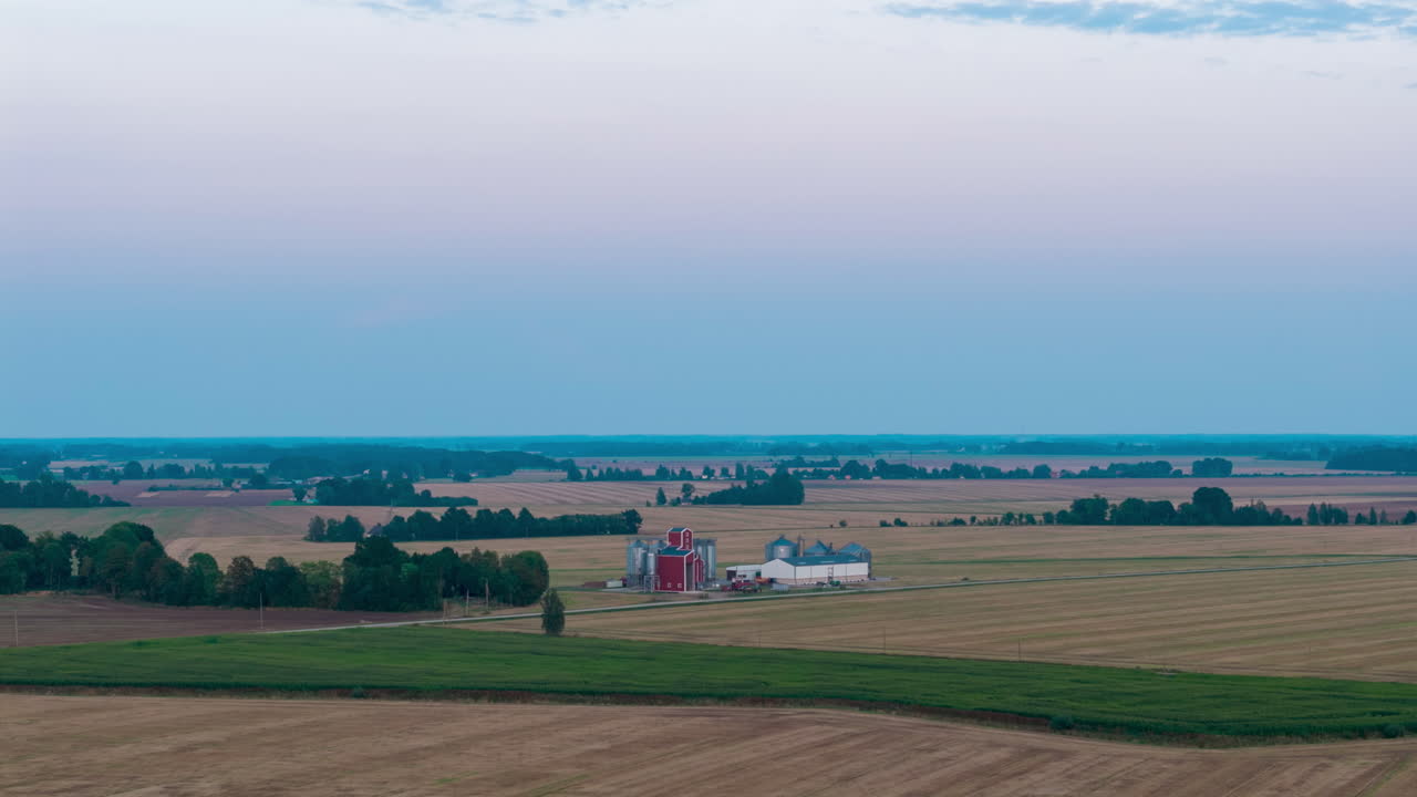 Aerial establishing of farmland grid pattern stretching to horizon under soft daylight