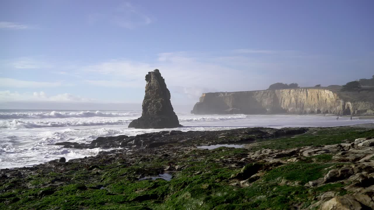 Big Rock Formation in the Ocean with Cliffs in the Background