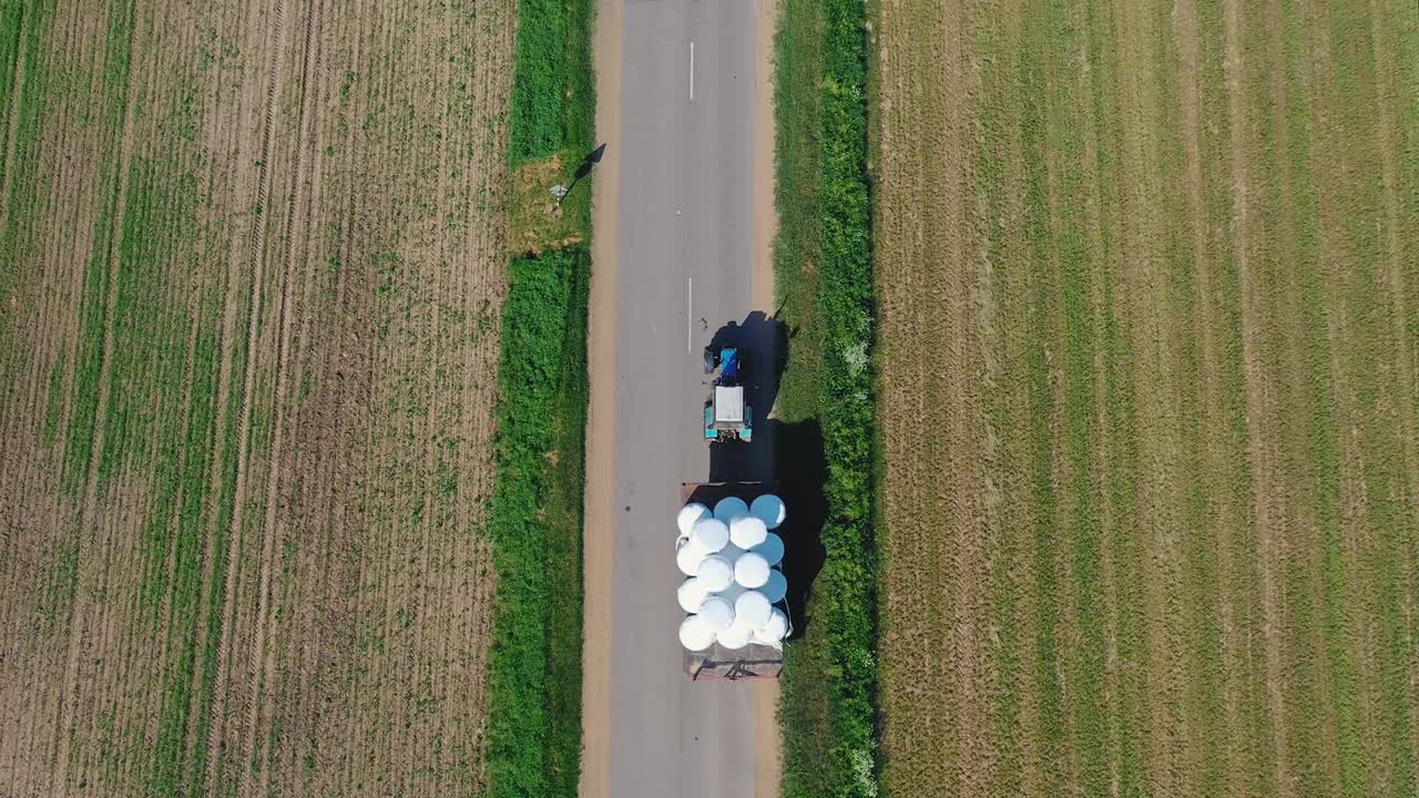 tractor aéreo que transporta rollos de heno en el remolque desde el campo hasta el almacén