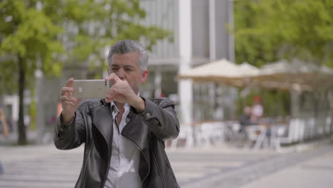 hombre elegante usando un teléfono inteligente en la calle