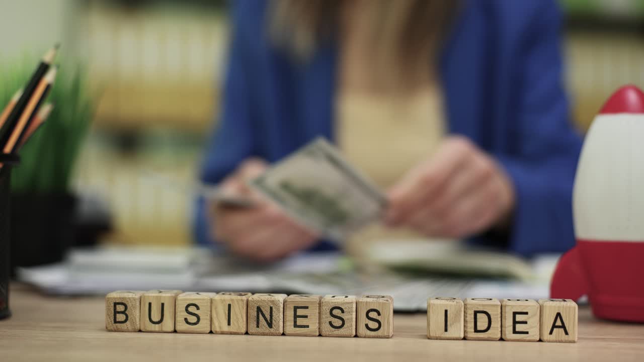 Houten blokken 'bedrijfsidee' met persoon die geld telt