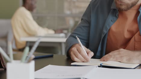 businessman writing down notes in notebook