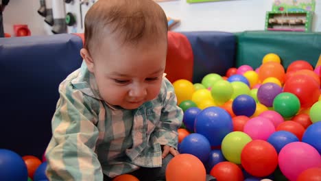 cute six months old baby boy playing with colorful balls in children indoors playground