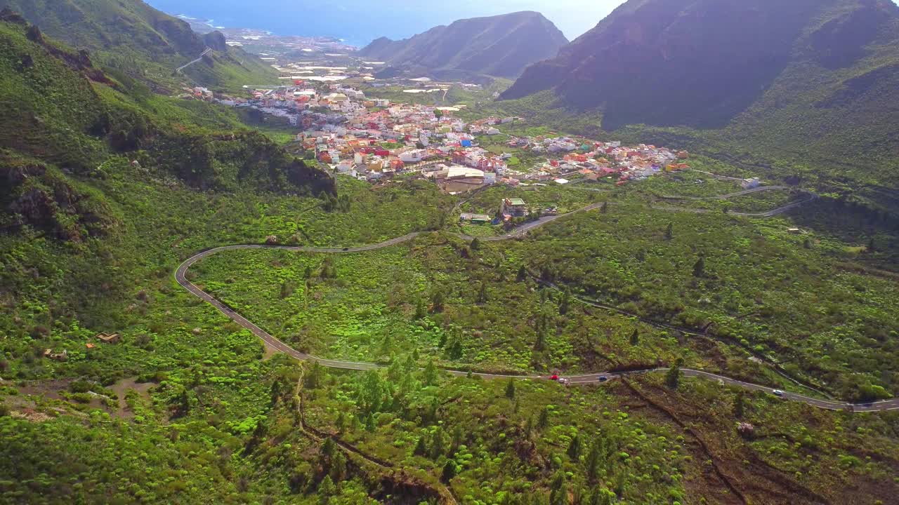 carretera con curvas que conduce a la pequeña ciudad de la isla de tenerife, vista aérea de drones