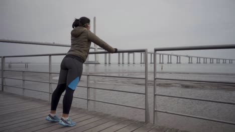 sporty young woman wuth headphones doing push ups from metal railings