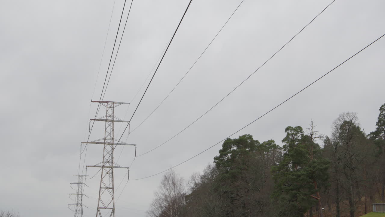 High voltage power lines running through suburban forest, slow tilt