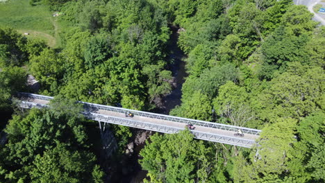 Grupo-De-Ciclistas-Bajando-Por-Un-Puente-En-Granby,-Quebec,-Canadá