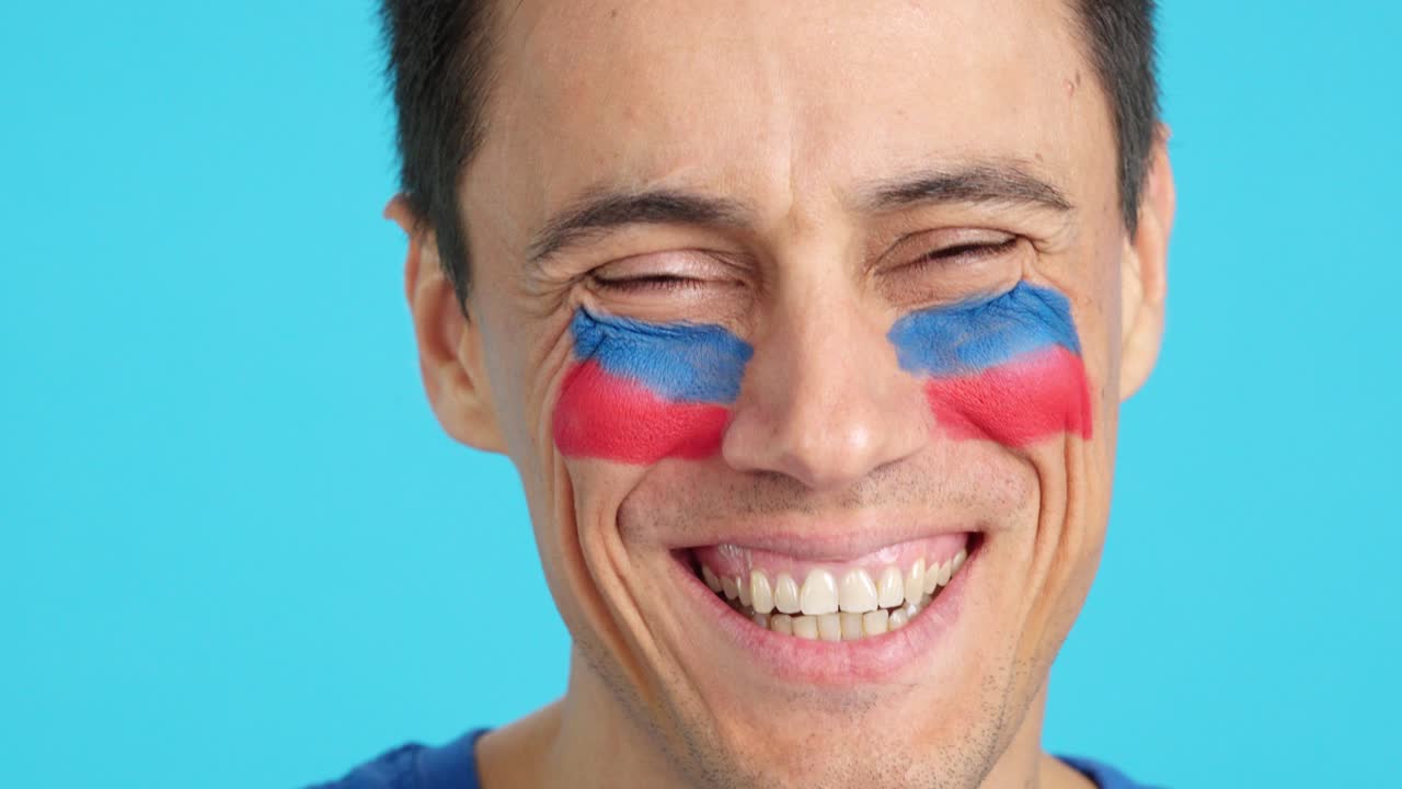 Man with a haitian flag painted on the face smiling