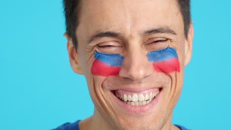 man with a haitian flag painted on the face smiling