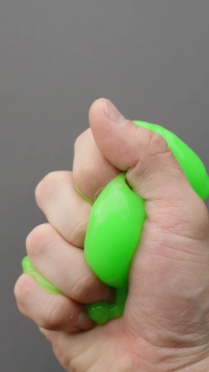 Hands playing with vibrant green slime, feeling playful and fun, vertical