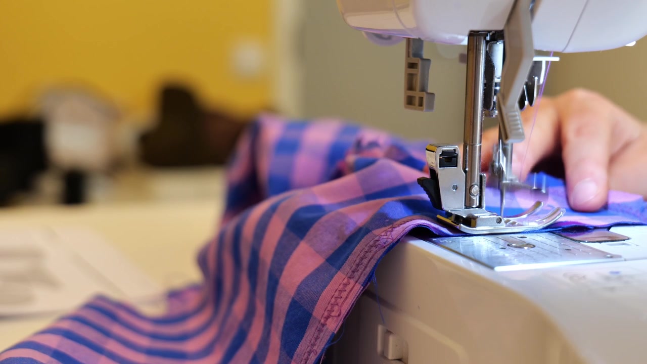 Close up of hand and sewing machine in work.