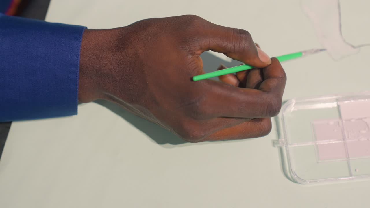 Sketch using colorful brush strokes. Closeup of hand applying paint to paper with precision and focus. Detailed view of hand painting sketch using bright palette and steady movement