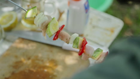 close up on hand adding cut vegetables to a skewer or brochette for barbecue