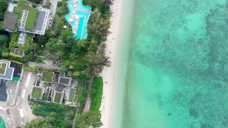 panning from the bottom going up while doing an overhead drone shot of the resorts at tri trang beach located in phuket island in thailand