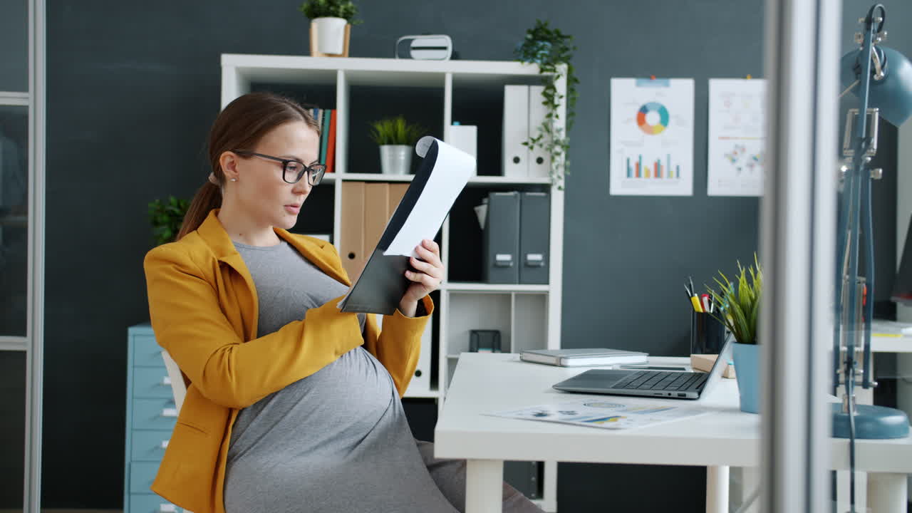 Imprenditrice incinta che esamina documenti in ufficio