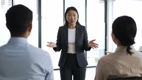 a confident female leader engages in a professional discussion with two individuals in a modern office setting, emphasizing effective communication and team dynamics